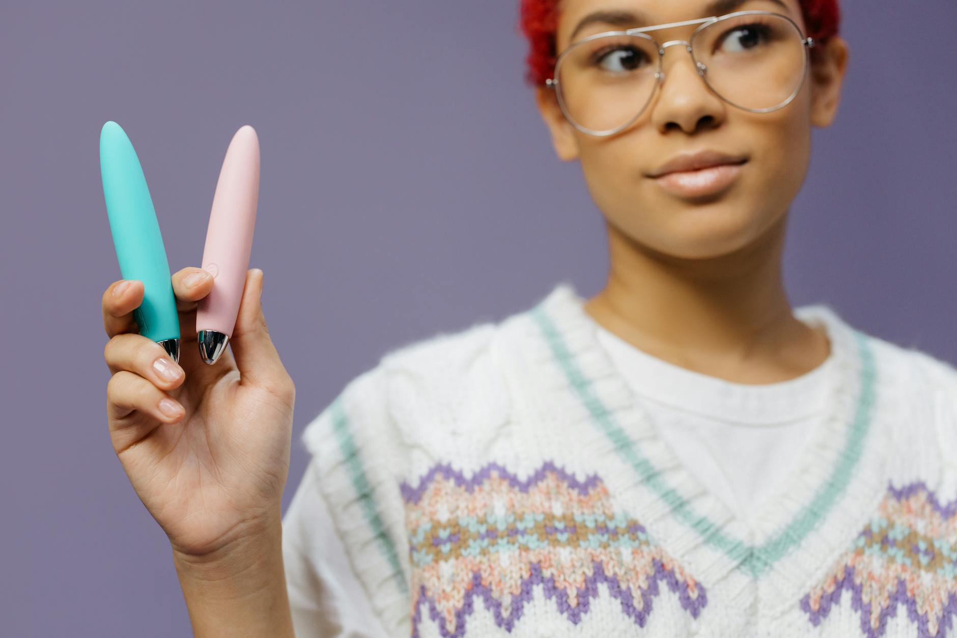 Woman holding colorful vibrators against a purple background, representing options for pleasure through life changes.