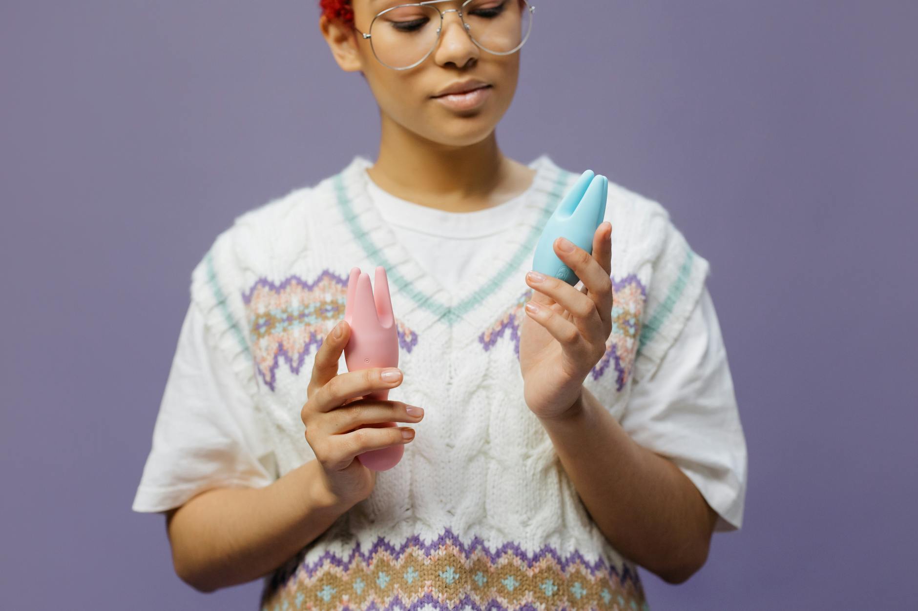 Woman holding a blue clitoral vibrator in contemplation, representing self-care and intimate wellness